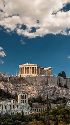 the acrobatic part of the city is surrounded by mountains and trees, under a blue sky with white clouds