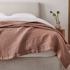 a bed with a brown blanket on top of it next to a wooden headboard