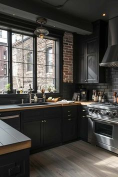 a large kitchen with black cabinets and stainless steel appliances, along with wooden flooring