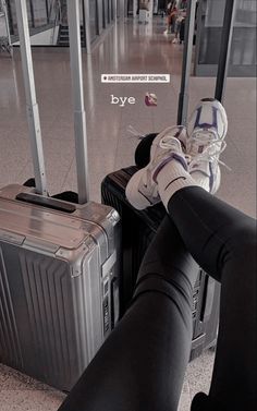 a person sitting on top of luggage in an airport terminal with their feet propped up