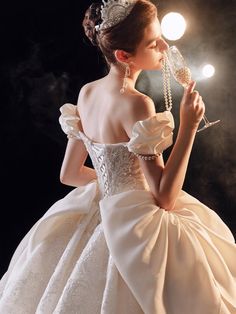 a woman in a white dress holding a crystal ball and wearing a tiara with pearls on it