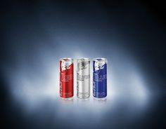 three cans of energy drink on a dark background with light coming through the top and bottom