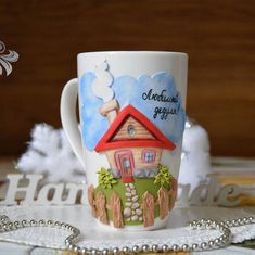 a coffee cup with a house painted on it