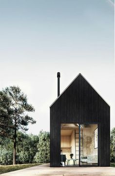 a small black house sitting in the middle of a field with trees and grass around it