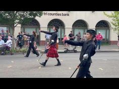 two men in kilts are dancing on the street