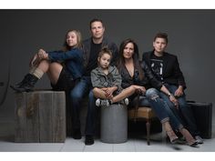 a group of people sitting next to each other in front of a gray background,