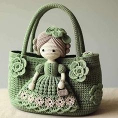 a crocheted bag with a little doll in the center and flowers on it