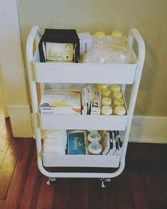 a white cart filled with lots of items on top of a hard wood floor next to a wall