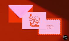 an orange and pink business card with a heart on the front next to a red envelope