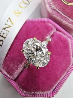 an oval diamond ring in a pink velvet box