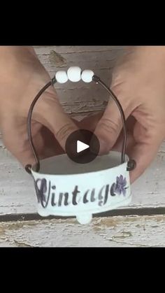 someone is holding a small bucket with the word vintage on it and beads hanging from it