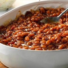 a white bowl filled with baked beans on top of a wooden table