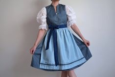 Vintage NOS blue pattern  dirndl dress with a sky blue apron, size 40 EU Traditional Oktoberfest dirndl dress with fitted upper part with a V neckline with high neck collar and flare above-the-knee skirt. The dress has an abstract geometric pattern in dark blue, the top closes with metal buttons, the crotch area of the skirt closes with tic tac hidden buttons. Has one handpocket, the top is lined with white fabric the skirt is not. The apron is light sky blue with contrasting detail on the botto Blue Fitted Dress For Oktoberfest, Fitted Blue Dress For Oktoberfest, Blue Dirndl, Dark Blue Tie, High Neck Collar, Folk Dress, Knee Skirt, Dirndl Dress, Blue Apron