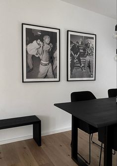 two black and white photographs hang on the wall above a dining table with chairs, bench