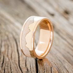 a gold wedding ring with an etched design on the inside, sitting on a wooden surface