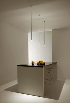 a white kitchen with an island and stools in the center, along with hanging lights