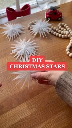 someone is making christmas stars out of paper and wood beads on a table with the words diy christmas stars over them