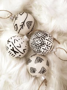 three white ornaments with black designs on them sitting on a fur covered surface in the shape of an ornament