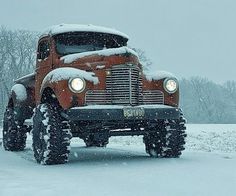 an old red truck is parked in the snow