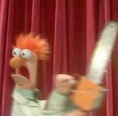 a cartoon character holding a chainsaw in front of a red curtain with his mouth wide open