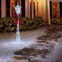 a street light with a red bow on it in front of a house at night