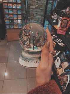 a person holding up a snow globe in front of a store display filled with toys