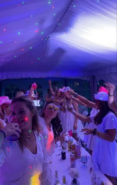 a group of people standing around a table with drinks and confetti on it