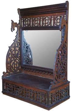 an antique wooden mirror with intricate carvings on the front and sides, sitting against a white background