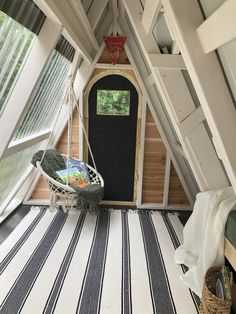 a small room with a black door and white striped rugs on the floor in front of it