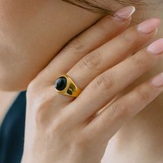 A modern interpretation of the classic signet ring, featuring a striking black onyx stone set in a bold gold-plated setting. The smooth, domed stone and architectural design create a sophisticated statement piece that commands attention. Specifications: Finish: 18K gold platedCore: Titanium steelGemstone: Black Onyx or Opal