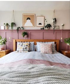 a bedroom with pink walls and wooden headboard, plants on the wall above the bed