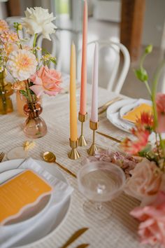 the table is set with candles and flowers in vases, plates and napkins