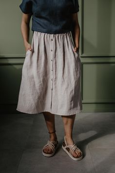 "A beautiful and comfortable midi length linen skirt with buttons DAISY. Comes with pockets on the side seam-line at the hips and seashell buttons at the front, with an elastic waistband. Great for many different styles and occasions, pair it with high heels for a dinner party or sneakers for a day in the city. Choose from 13 colors and 6 sizes. Details  This listing is for 1 DAISY linen skirt with buttons Model Emile is 168cm/5'5\" and wearing cream DAISY in size S. Available in sizes XS, S, M, Skirt With Buttons, Cute Aprons, European Linens, Skirt With Pockets, Linen Bag, Linen Skirt, Linen Apron, Color Swatches, Linen Clothes