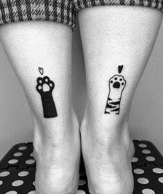 two people with matching tattoos on their legs, one has a dog and the other has a cat