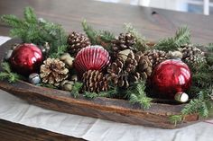 a wooden tray filled with pine cones and ornaments