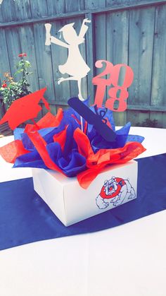 a white box with red and blue tissue paper on it sitting on top of a table