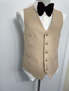 Goodmorning! This is a Vintage 1960s era  beige cream wool pleated hip pocket suit vest/ waistcoat. This suit vest waistcoat features five-button front closure and two front and side hip jetted pockets.. This is a great find and superb find for vintage enthusiast lovers. Excellent great fi Estimated size: 40 : Please see measurement below , for best fit compare measurement with similar vest waistcoat or item. Armpit to Armpit: 21" Front Length: 24.50" Condition: For its age , this suit vest is i Fitted Gold Vest Elegant Style, Fitted Gold Elegant Vest, Gold Fitted Vest, Elegant Gold Fitted Vest, Beige Single Breasted Vest For Formal Occasions, Beige Single-breasted Vest For Formal Occasions, Beige Sleeveless Semi-formal Vest, Elegant Wedding Vest With Buttons, Classic Tailored Wedding Vest