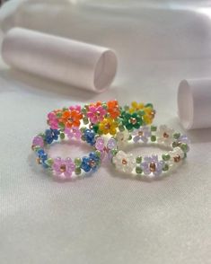 three bracelets with flowers on them sitting on a white surface next to some plastic tubes