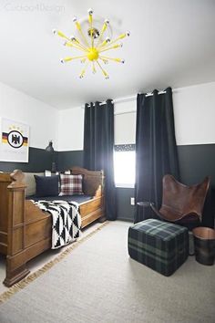 a bedroom with black and white walls, plaid rugs, wooden furniture and a yellow chandelier hanging from the ceiling