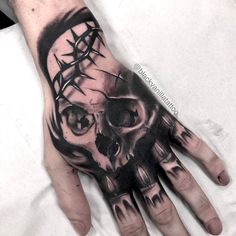 a hand with a skull and crown tattoo on it