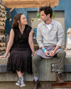 a man sitting next to a woman on top of a cement wall