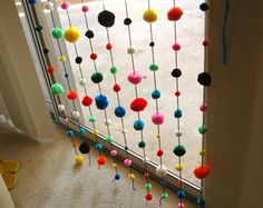 a window decorated with pom - poms and hanging from it's side