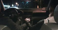 two people are sitting in the driver's seat of a car at night time