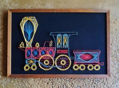 a blackboard with colorful crochet on it and a toy train in the middle