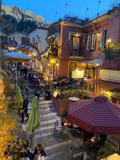 an outdoor restaurant with tables and umbrellas on the steps leading up to some buildings