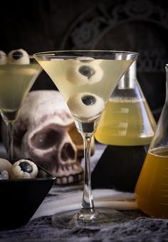 two glasses filled with liquid next to skulls