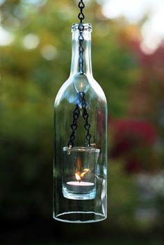 a candle in a glass bottle hanging from a chain