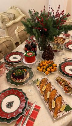 a table set for christmas dinner with plates, silverware and fruit on the table