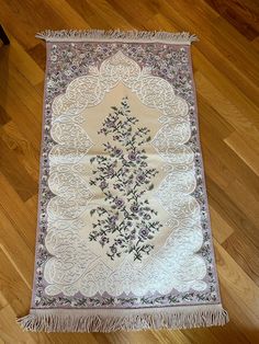 a white rug with purple flowers on it sitting on top of a hard wood floor