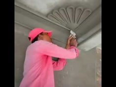 a man in pink is painting the ceiling